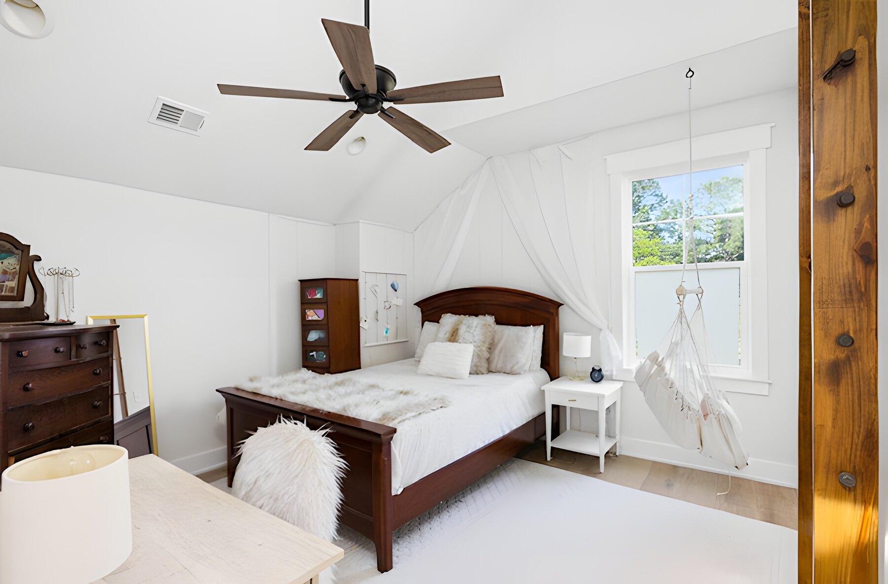 Vaulted bedroom with ceiling fan and hammock chair