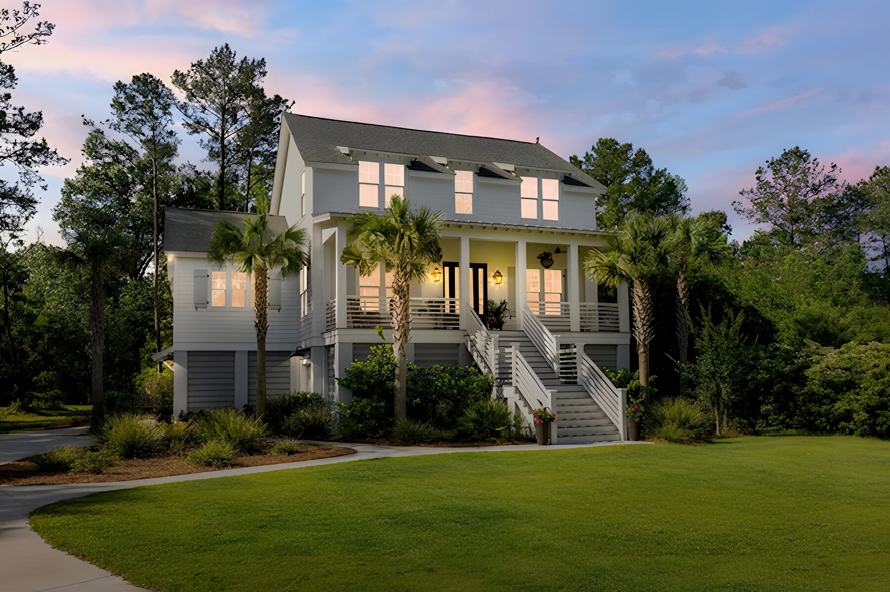 Seascape Homes custom Lowcountry home at dusk with glowing porch and palms